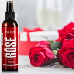 A styled shot of Urban Botanics rose water with fresh red roses and a gift box. This setup evokes a sense of romance and luxury, connecting the product to its core natural ingredient.