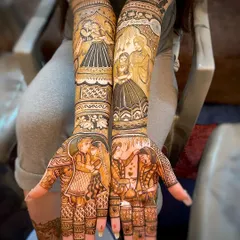 A full view of a narrative bridal mehndi, featuring multiple couple portraits and scenes from their story. The design extends from the palm to the full arm, creating a cohesive piece of art.