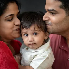 The safest place in the world. This close-up captures the tender love of parents for their child, a quiet moment of affection that speaks volumes. These are the intimate family portraits we love to create.