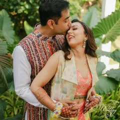 A joyful hug from behind, the groom surprising the bride with a tender kiss on the head during their Haldi photoshoot.