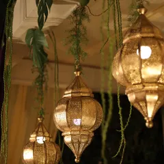 Golden Moroccan-style lanterns hanging amidst lush greenery, adding a warm and exotic glow to the decor.