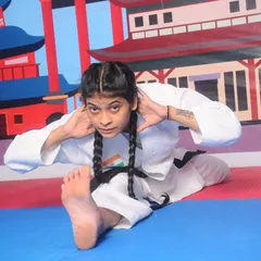A black belt student performs an advanced hamstring and back stretch, showcasing the high level of flexibility required for executing complex karate movements.
