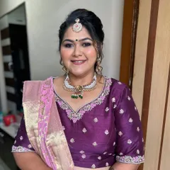 A lovely and elegant look for a wedding guest. The makeup is soft and defined, with a purple-toned eyeshadow to complement her beautiful silk saree.