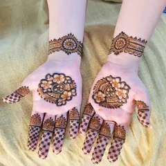 A lovely and dainty Eid henna design. The palms feature a small floral and paisley motif, with a delicate grid pattern on the fingers.