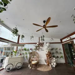 The full view of the baby shower setup in a beautiful, light-filled room. The hanging plants and greenery wall add to the 'in bloom' theme.