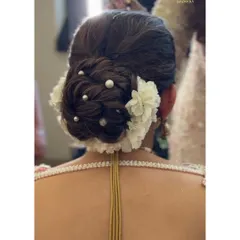 A detailed view of a textured bridal bun, adorned with fresh white flowers and delicate pearls for a classic and elegant wedding day look.
