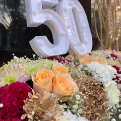 A close-up of the 50th birthday centerpiece. I used a mix of peach roses, red carnations, and white and gold chrysanthemums for a warm and celebratory color palette.