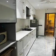 This angle shows the kitchen's appliance integration, with designated spots for the refrigerator and microwave. The consistent design of the cabinetry creates a cohesive and highly organized culinary workspace.