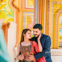 An intimate portrait framed by the colorful frescoes of a Rajasthani palace. The soft light and gentle embrace create a moment of pure romance.