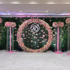 For a fresh, daytime corporate event or launch, I can create a stage like this one. It features a lush green wall, a central floral ring with custom monogramming, and clean, elegant lines that feel both natural and professional.