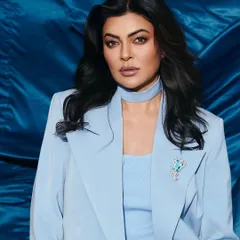 A close up portrait of Sushmita Sen in the powder blue suit. The look is elevated by the matching choker and a beautiful aquamarine brooch, adding a touch of personalized glamour.
