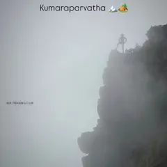 A trekker stands triumphantly on a rocky outcrop at Kumaraparvatha. The dense fog adds to the mystery and adventure of this challenging Western Ghats expedition.
