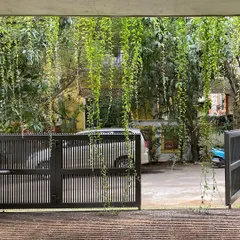 A view from the carport of "House of Greens," looking out through the gate. The cascading greenery frames the view and creates a sense of being enveloped by nature.