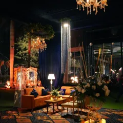 A luxurious and moody decor setup for an evening event, with rich colors, dramatic lighting, and plush seating.