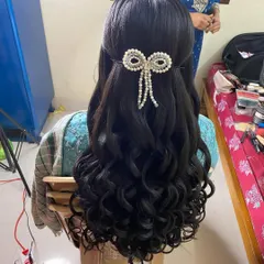 A behind-the-scenes look at the reception hairstyle. You can see the beautiful curls and the pearl bow accessory being styled to perfection.