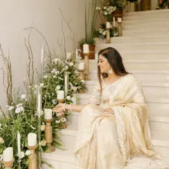 A candid moment from a beautifully styled 50th and 80th birthday celebration. The staircase was decorated with an organic arrangement of white flowers, fresh greenery, and candles in wooden holders, creating a soft, romantic ambiance.