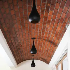 I believe ceilings are a fifth wall waiting for a story. This exposed brick vault ceiling, accented with minimalist pendant lights, creates a warm, dramatic corridor and showcases a love for textural details.
