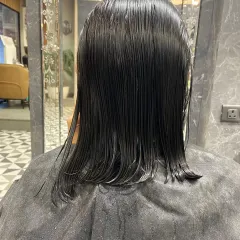 The "before" shot of a client ready for a major chop. Her shoulder-length wet hair is prepped for a transformation into a sleek bob.