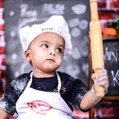 Holding the rolling pin like a pro! The little details, like the dusting of flour on his cheek, make these 'Little Chef' portraits so authentic and charming.