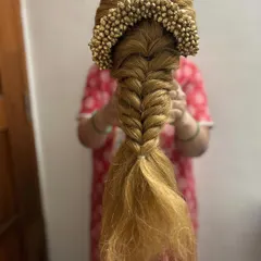 A fishtail braid paired with a golden floral accessory, created on a mannequin head. This is a great example of how we practice combining traditional and modern elements in my hair education classes.