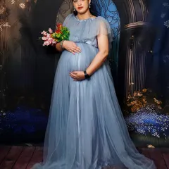 A solo portrait of the mom-to-be from the same session, holding a bouquet and cradling her bump in a beautiful blue gown.