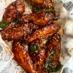 Here are the same Inji Puli Chicken Wings, served casually in branded paper, ready for takeaway. Sprinkled with sesame seeds and curry leaves, they are perfect as a party starter or a delicious treat for a day at home.