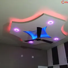 For this bedroom, we installed a dynamic false ceiling with multi-color LED lighting options. The design allows the client to change the room's ambiance with remote-controlled red, blue, and purple lights, highlighting the curved and layered structure.