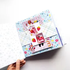 An interactive waterfall card in a baby scrapbook, perfect for showing monthly milestone photos from the first year.