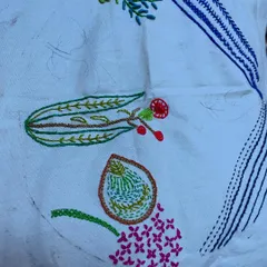 Another stage of the floral hoop art project. The combination of different stitches, like the satin stitch for petals and stem stitch for branches, creates a rich and varied texture.