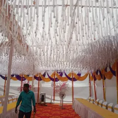 This is the interior of a large mandap I set up for an event. The ceiling is decorated with hanging white paper ribbons, while the sides feature traditional yellow and purple drapes over the seating area.