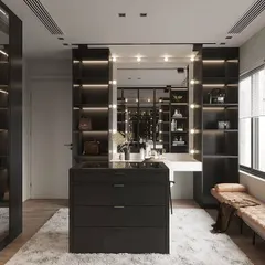 This spacious dressing room is designed for the modern fashion lover, with open, backlit shelving for bags and accessories. A central island drawer unit and a Hollywood-style vanity mirror complete the look.
