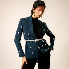 A chic and modern look for a London-based designer. This shot highlights a tailored blazer with unique embellishments, styled with a pearl belt for a touch of elegance.