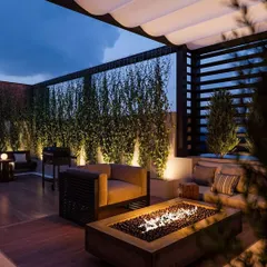 This luxury terrace is designed for entertaining, featuring a modern fire pit, comfortable deep-seated sofas, and a vertical garden wall. The retractable awning provides flexibility for both sunny days and starry nights.