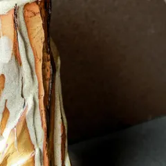 A close-up of a Kurinuki vase, showing the deep, chiseled textures that mimic a mountain facade. The process is sculptural, revealing the form as I carve away the clay.