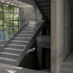 A steel and concrete staircase takes shape within the Courtyard House. The image shows the raw structure and the interplay between different materials before the finishing touches are applied.
