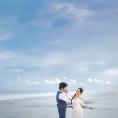 A gentle kiss on the hand with the vast Bali coastline behind you. This wide shot captures both the intimate gesture and the epic scale of the destination.