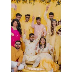 A fantastic group photo with the couple and their friends during the Haldi. It’s a moment of shared celebration, with flower petals flying and everyone dressed in vibrant yellows.