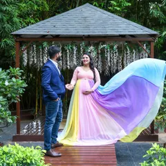 A fairytale moment for this couple. The mom-to-be is wearing our flowing rainbow pastel gown, creating a magical scene in a beautiful garden setting.