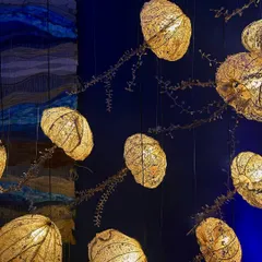 An intricate lighting installation made of gilded, pod-like forms. This piece showcases a beautiful combination of natural inspiration and refined craftsmanship.