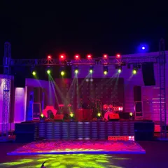 A stage setup ready for a live band or DJ performance at a cocktail party. The arrangement includes a drum kit, speakers, and a full rig of colourful spotlights to create a vibrant and energetic atmosphere.