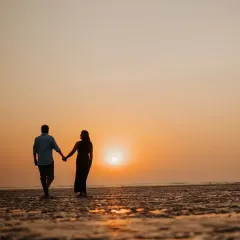 A classic silhouette of the couple walking hand-in-hand towards the sunset. This is the epitome of beach romance, a timeless image of two people starting their journey together.