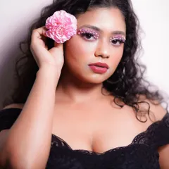 A creative makeup look featuring pink eyeshadow adorned with tiny pearls. The embellishments are placed along the upper and lower lash lines for a unique, textured effect.