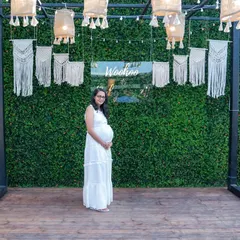 A serene portrait of an expectant mother standing before a stylish boho-themed backdrop at her baby shower. We offer baby shower photography that matches your event's aesthetic.
