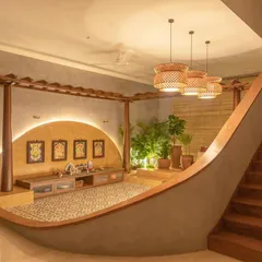This modern puja room is designed as a tranquil, sacred space within the home. The curved, sunken seating area, warm backlighting, and traditional floor tiles create a serene spot for prayer and reflection.