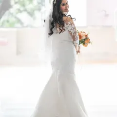 A classic bridal portrait with a modern twist. The bride looks over her shoulder with a confident smile, showing off the beautiful back of her mermaid-style wedding dress.
