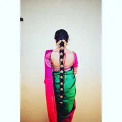 A full back view of a traditional bridal hairstyle. The long braid is decorated with gold-colored floral accessories, perfectly matching the bride's temple jewellery.