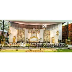 A full view of this elegant wedding reception stage at Sumatra Wedding Venue in JP Nagar. The design features panels of dense white and pink flowers, a central floral crest, and a beautifully arranged foreground, creating a classic and luxurious backdrop.
