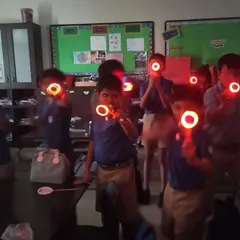 Students in a classroom hold up their glowing creations, a fun and visual way to learn about basic electronics and circuits.
