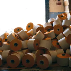 A behind-the-scenes look at the textile creation process. This image captures the abundance and raw texture of the yarn cones before they are woven into fabric, telling the story of beginnings.