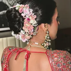 A detailed look at a floral bridal bun, featuring a mix of pink hydrangeas and other delicate flowers. This style adds texture and romance to a traditional updo.